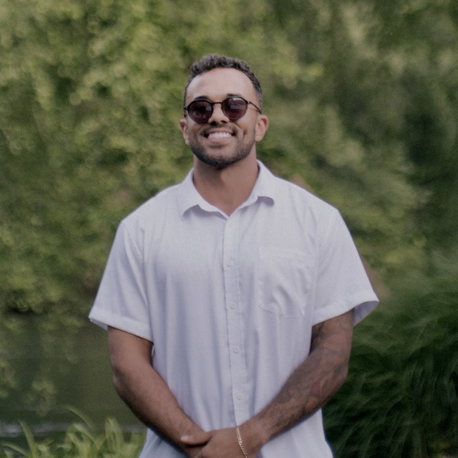 Micah Rock, smiling outside in a white shirt